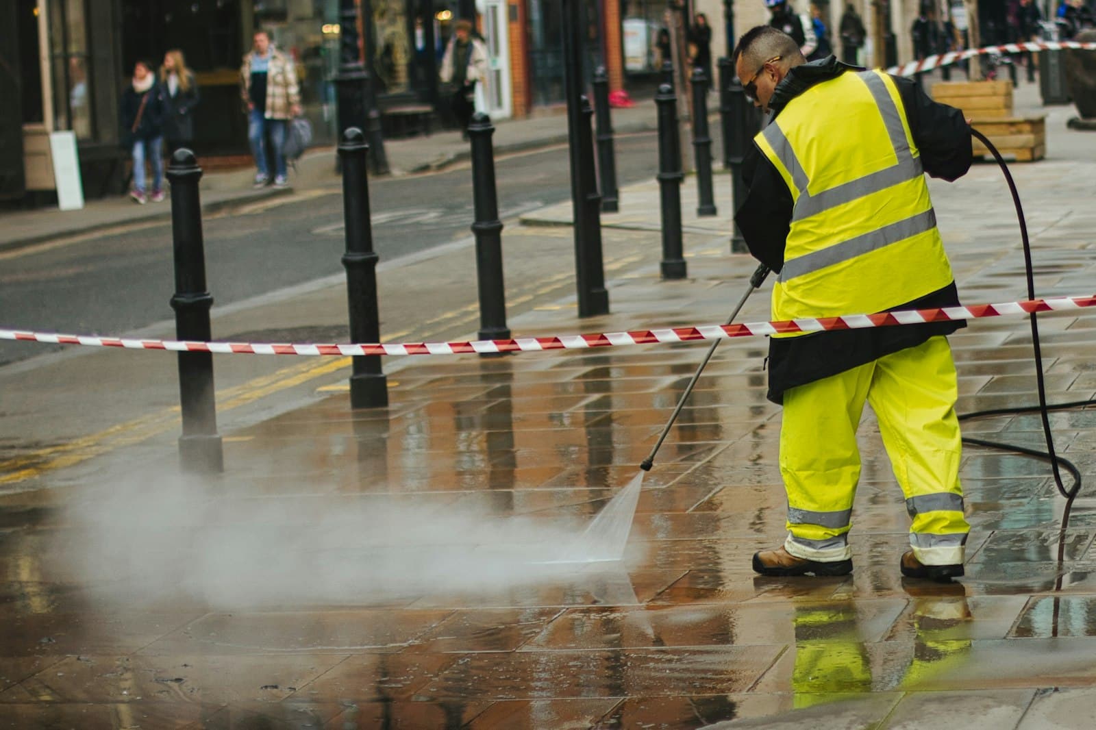 Worker cleaning paving with a pressure washer