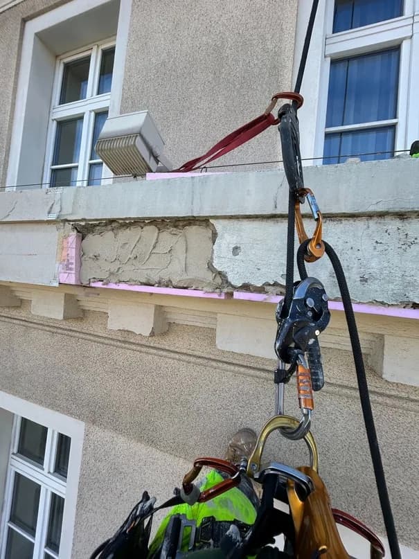 Poškodená rímsa historickej budovy s odpadnutou omietkou